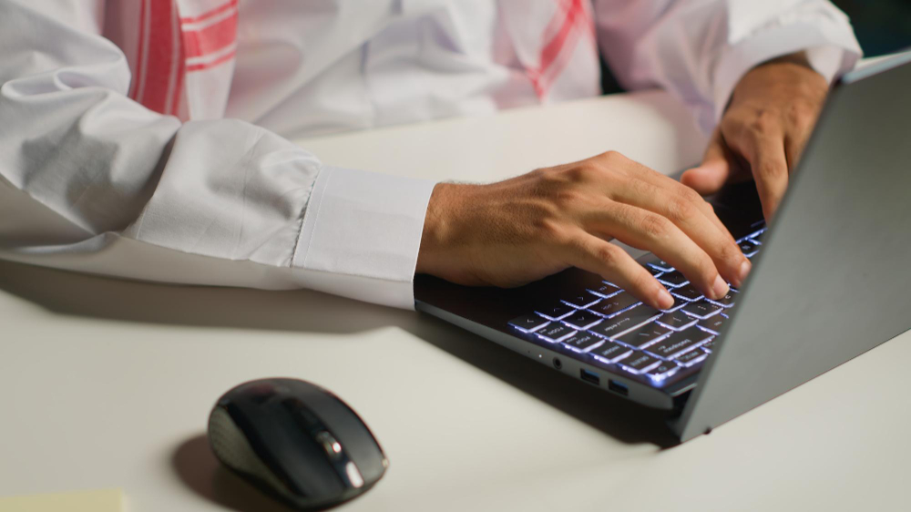 Saudi professional working on laptop in modern office environment