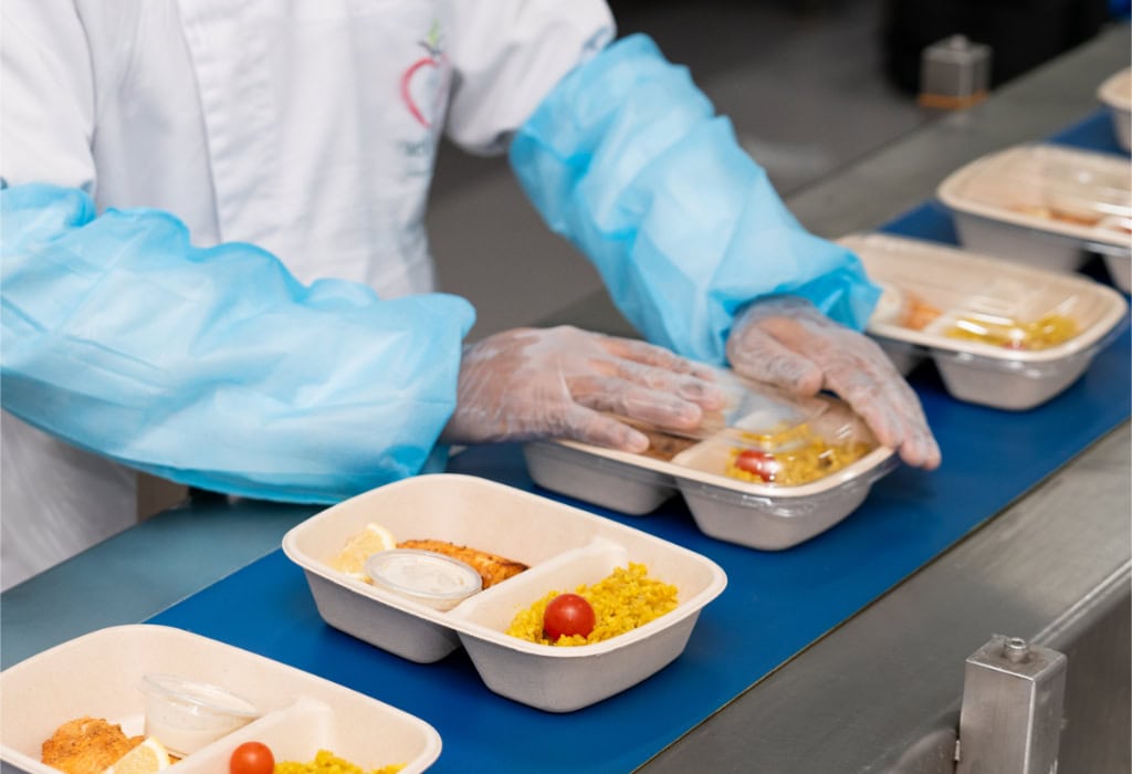 Diet Center staff member at tray line prepare meals on a production line